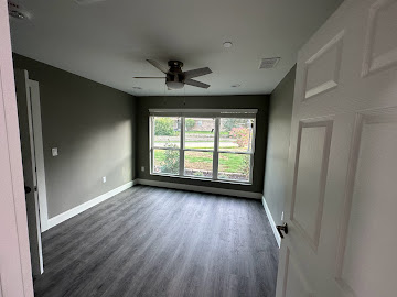 Freshly painted bedroom with new luxury vinyl plank flooring and ceiling fan