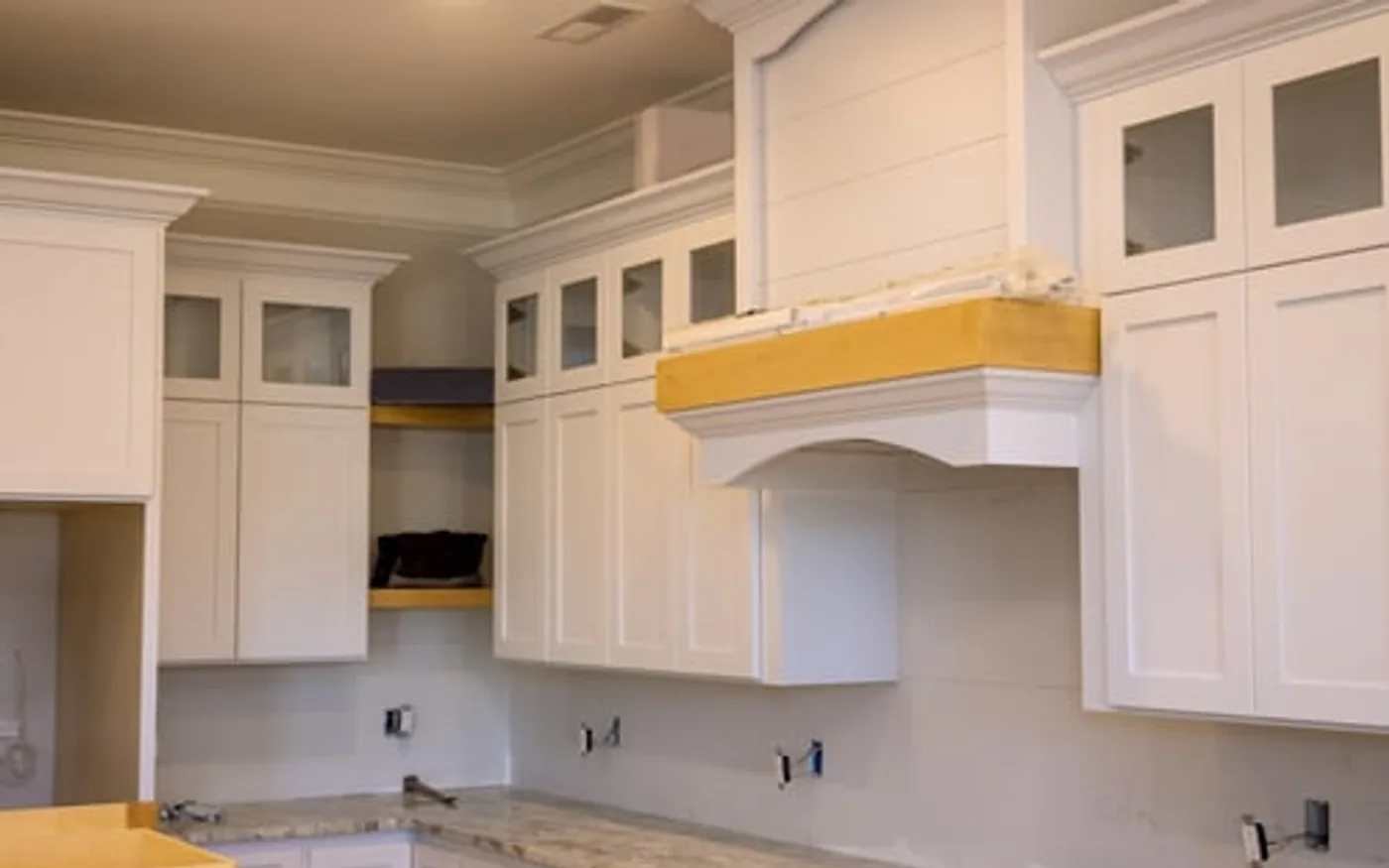 Refinished white kitchen cabinets with a range hood and stone countertop after a cabinet update