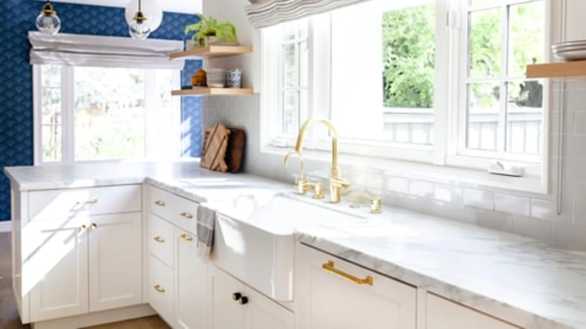 Completed kitchen remodel with white cabinetry, marble counters and gold fixtures
