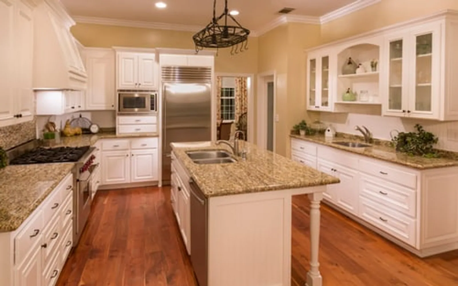 Newly installed white kitchen cabinets with a granite island and pendant lighting